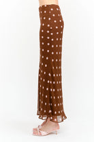 Kalila Midi Skirt in rich brown featuring soft pink polka dots, a flattering mermaid silhouette, and a flowing ankle-grazing hem.
