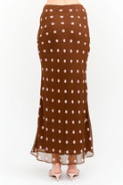 Kalila Midi Skirt in rich brown featuring soft pink polka dots, a flattering mermaid silhouette, and a flowing ankle-grazing hem.