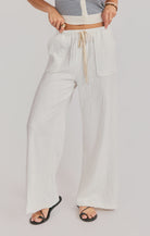 Person wearing light-colored wide-leg pants with a drawstring on a plain background