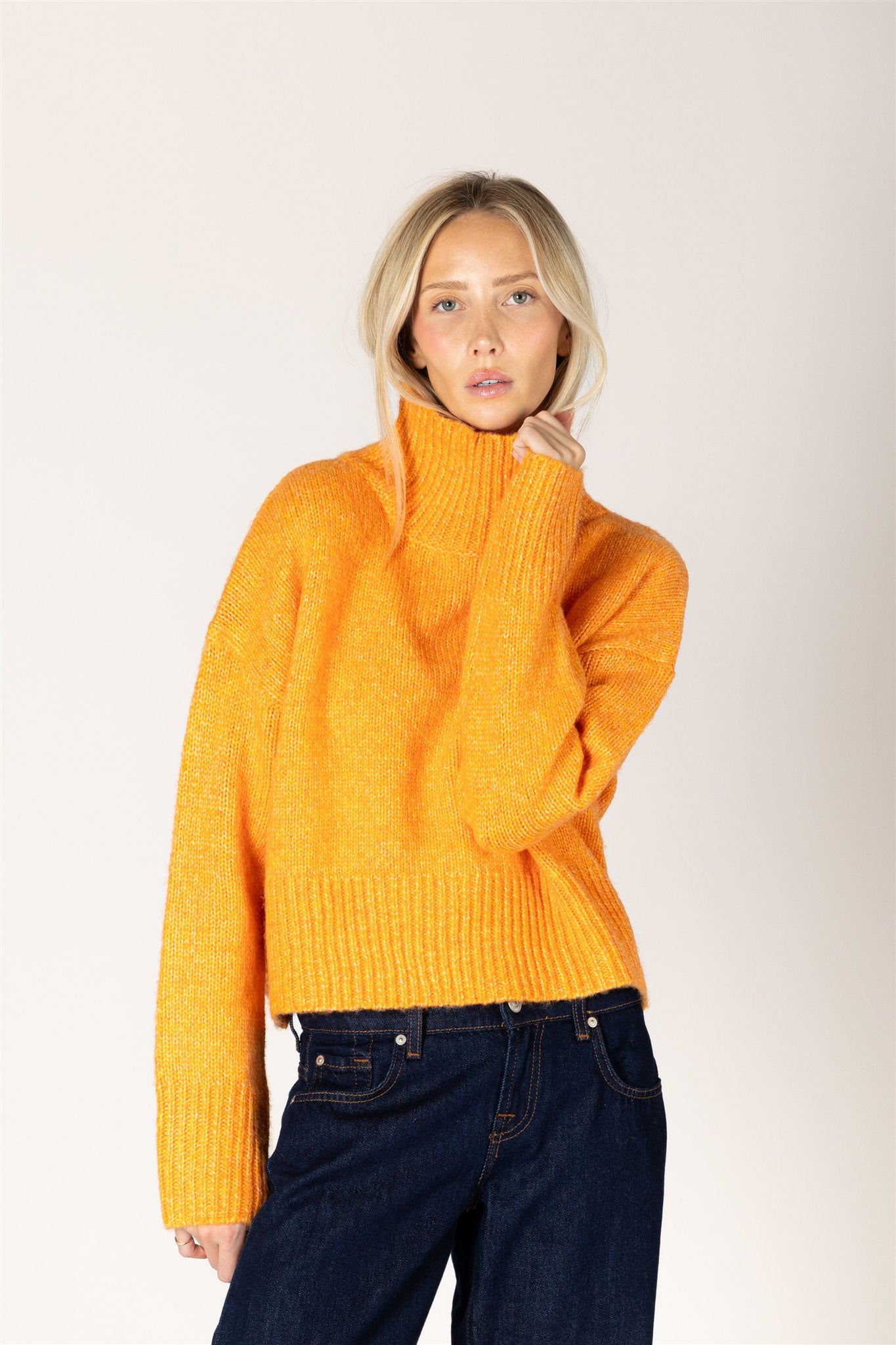 Amber yellow knit sweater featuring a mock neckline, relaxed fit, dropped shoulders, long sleeves, and ribbed cuffs and hem.