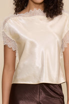 Lucy Paris Chris Lace Trim Top in ivory featuring a silky finish, relaxed fit, and delicate sheer lace trim along the neckline and short sleeves.