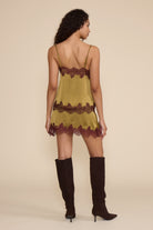 Claire Mini Skirt in chartreuse featuring a satin finish with burgundy contrast lace trim along the waist and hem.