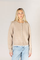 Lightweight knit cardigan featuring a classic crew neckline, button-front closure, long sleeves, and delicate lace trim along the hem and cuffs.
