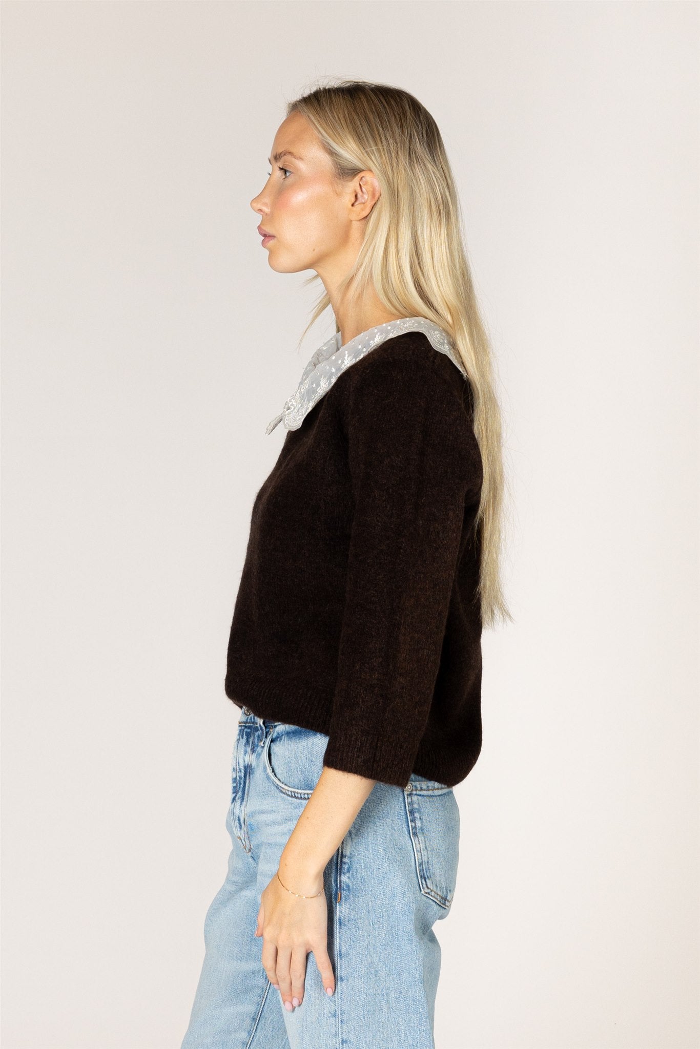 Knit sweater featuring a delicate lace collar, long sleeves, and a relaxed silhouette for a feminine, layered look.
