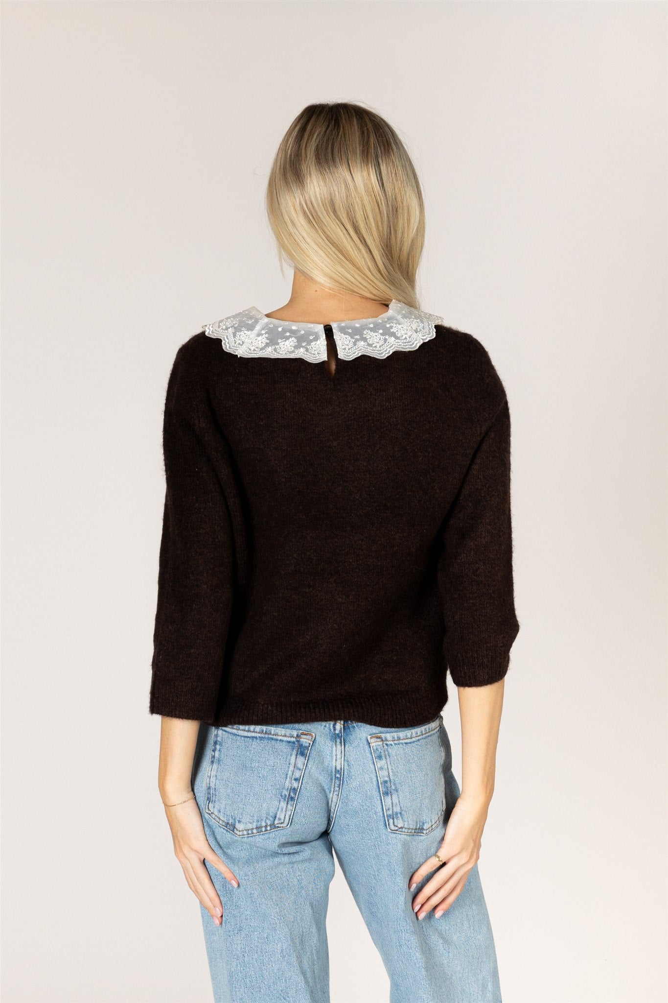 Knit sweater featuring a delicate lace collar, long sleeves, and a relaxed silhouette for a feminine, layered look.
