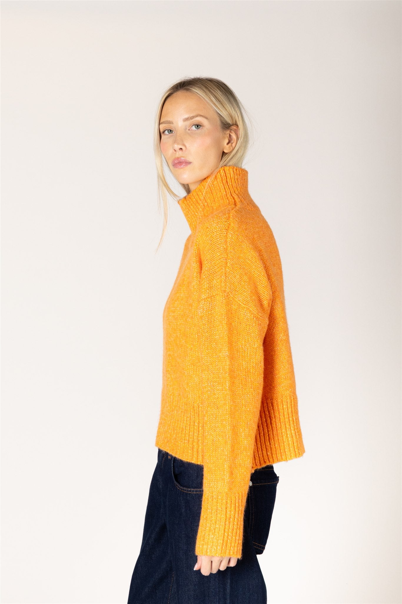 Amber yellow knit sweater featuring a mock neckline, relaxed fit, dropped shoulders, long sleeves, and ribbed cuffs and hem.