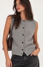 Heather grey knit vest with a sleeveless silhouette, round neckline, contrast button-front closure, and ribbed trim along the neckline, armholes, and hem. Designed with a clean, versatile fit for easy layering.
