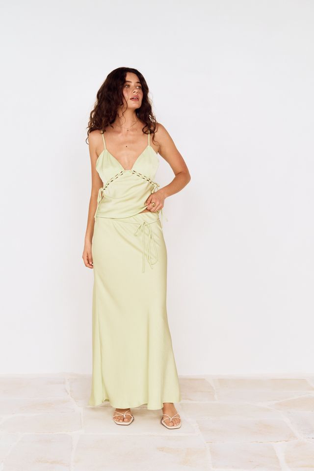woman wearing a lime lace and silky maxi skirt with a tie around the waist paired with the matching lace top
