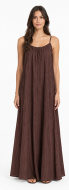 Model is wearing a chocolate-brown and white striped maxi dress with a relaxed, flowing floor-length silhouette and adjustable spaghetti straps.
