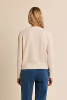Short knit cardigan featuring long sleeves, a delicate lace-trimmed V-neckline, and classic full-length button-front closure.
