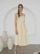 woman wearing an embroidered pintuck detail spaghetti strap midi dress in butter yellow
