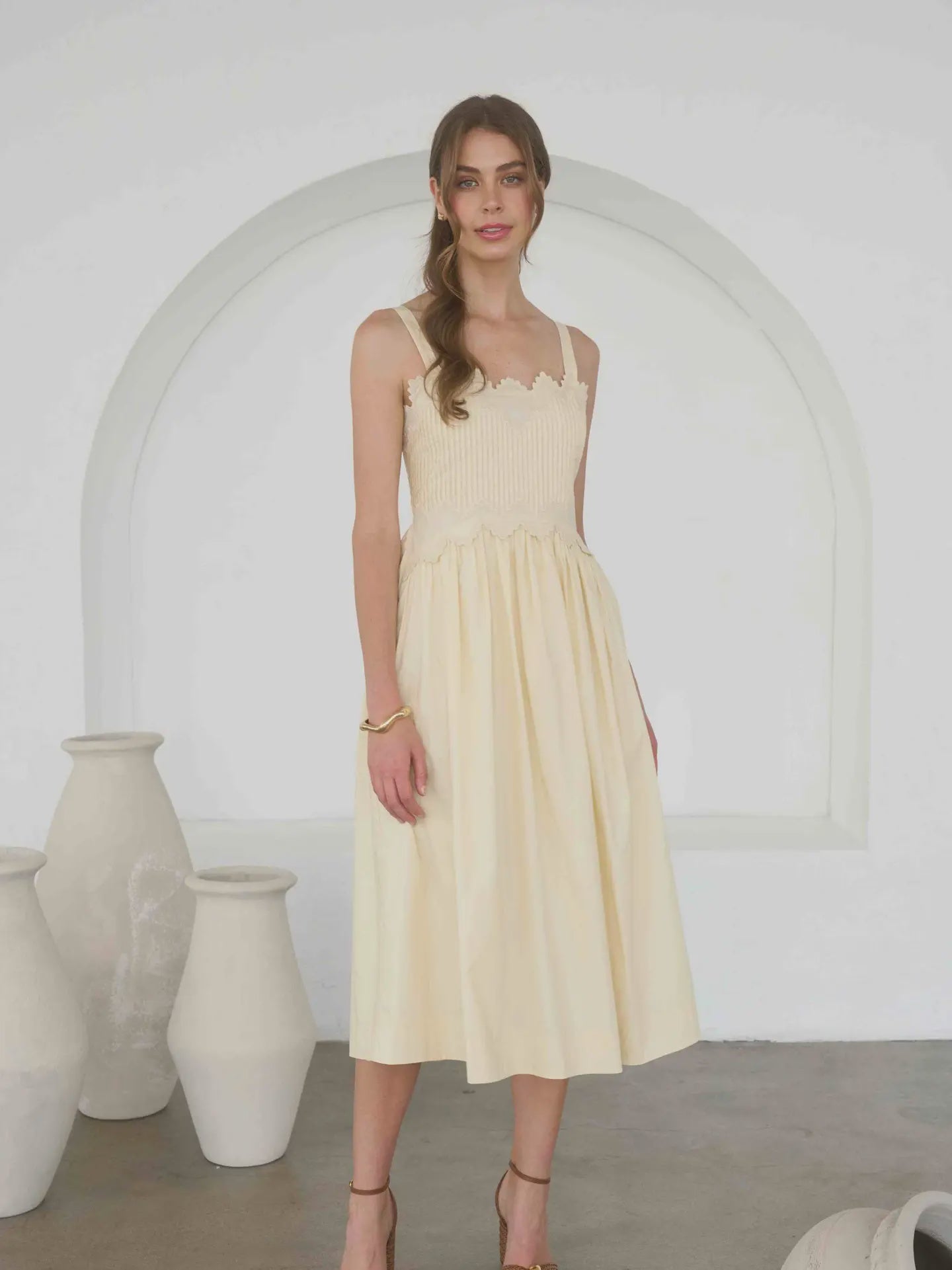 woman wearing an embroidered pintuck detail spaghetti strap midi dress in butter yellow