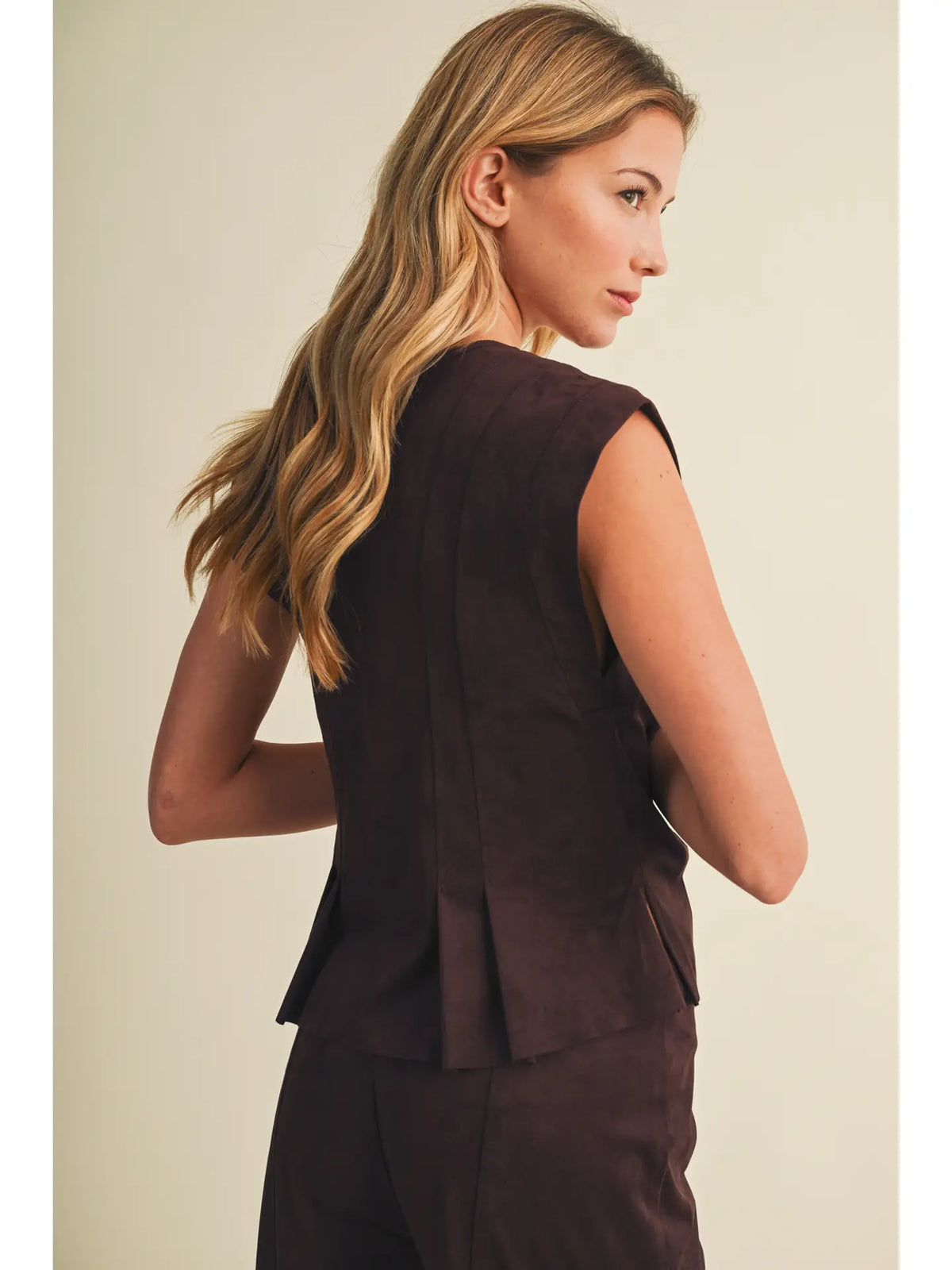 Faux suede sleeveless top with a V-neckline, button-front closure, extended shoulders, princess seams, and pleated peplum hem. Model is 5'9" and wearing a size Small.