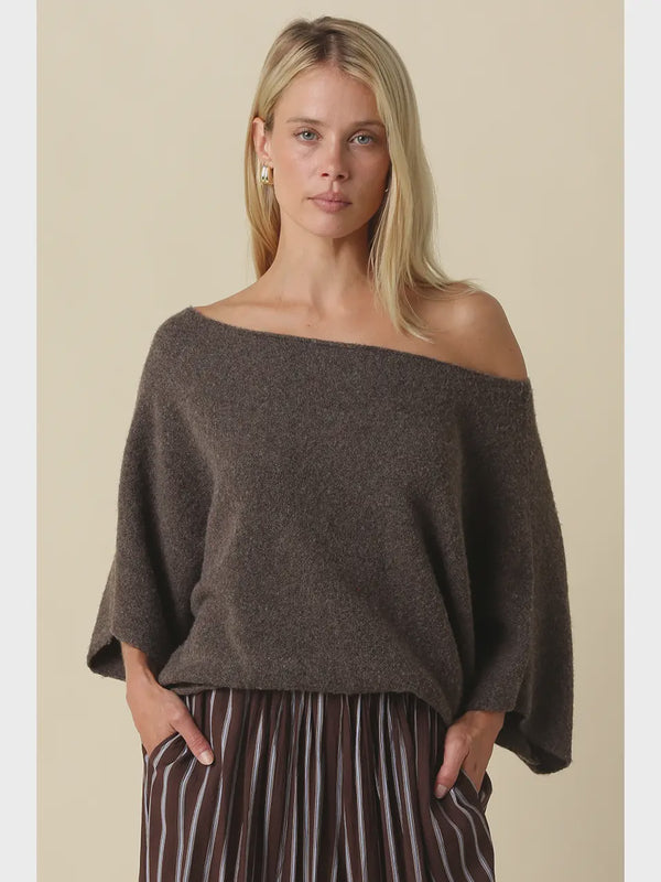 Oversized knit top with a one-shoulder neckline, dolman sleeves, textured finish, and relaxed draped fit.