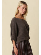 Oversized knit top with a one-shoulder neckline, dolman sleeves, textured finish, and relaxed draped fit.