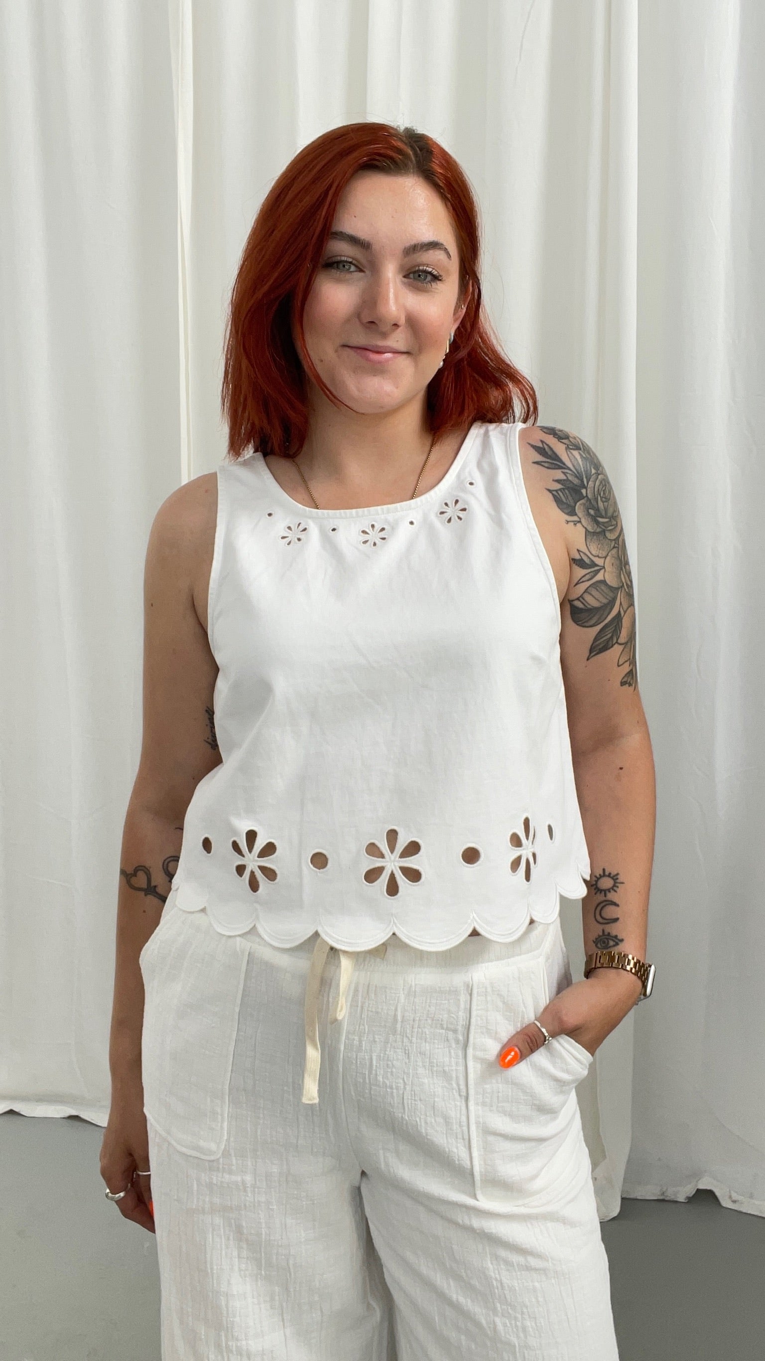 Woman wearing a white sleeveless top with floral cutouts 