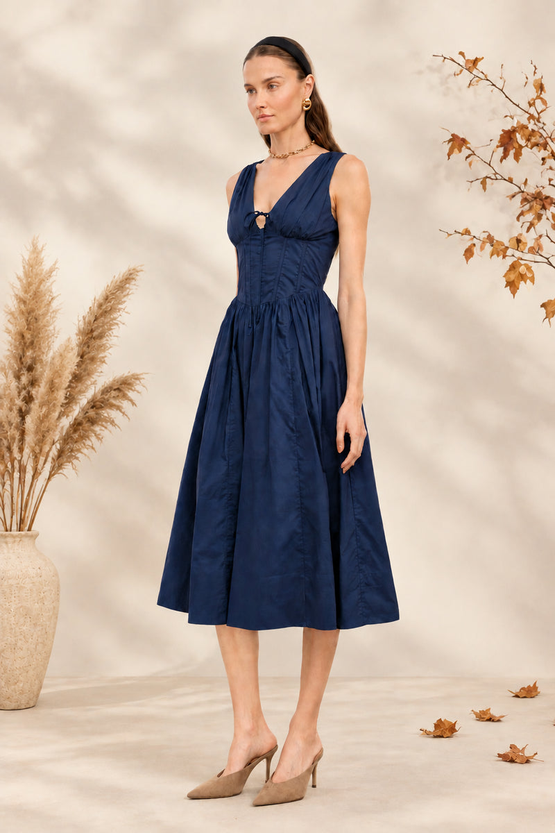 Shae Poplin Midi Dress in navy featuring a corset-inspired fitted bodice, plunging V-neckline, gathered bust with tie-front detail, defined waist, and full midi-length skirt.