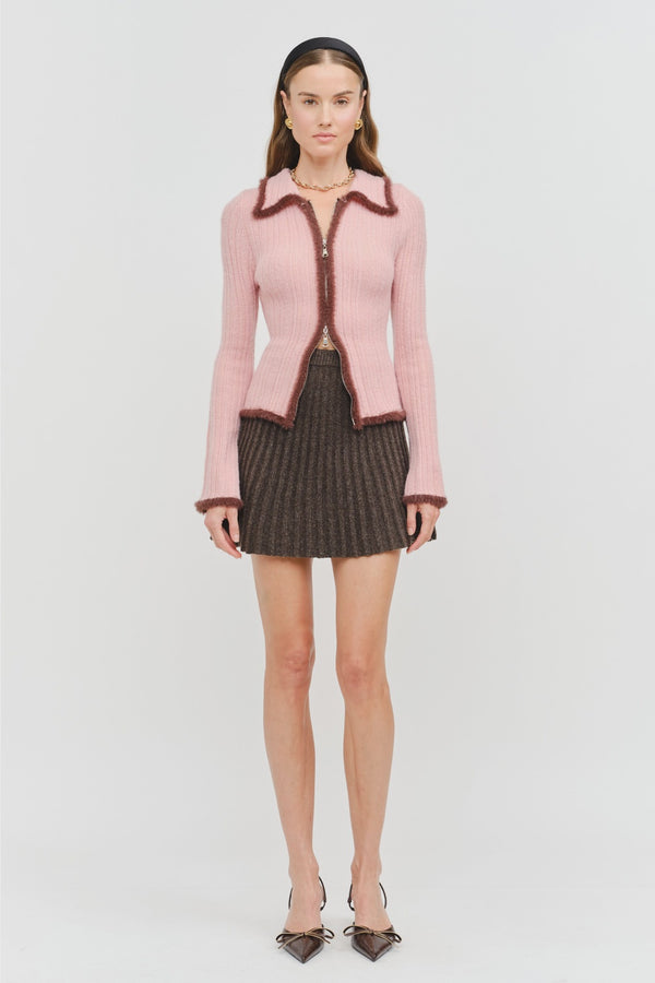 Model wearing the Jacquie Knit Top in light pink, featuring a fitted silhouette, long sleeves, collared neckline, contrasting burgundy fuzzy trim, and two-way front zipper closure.