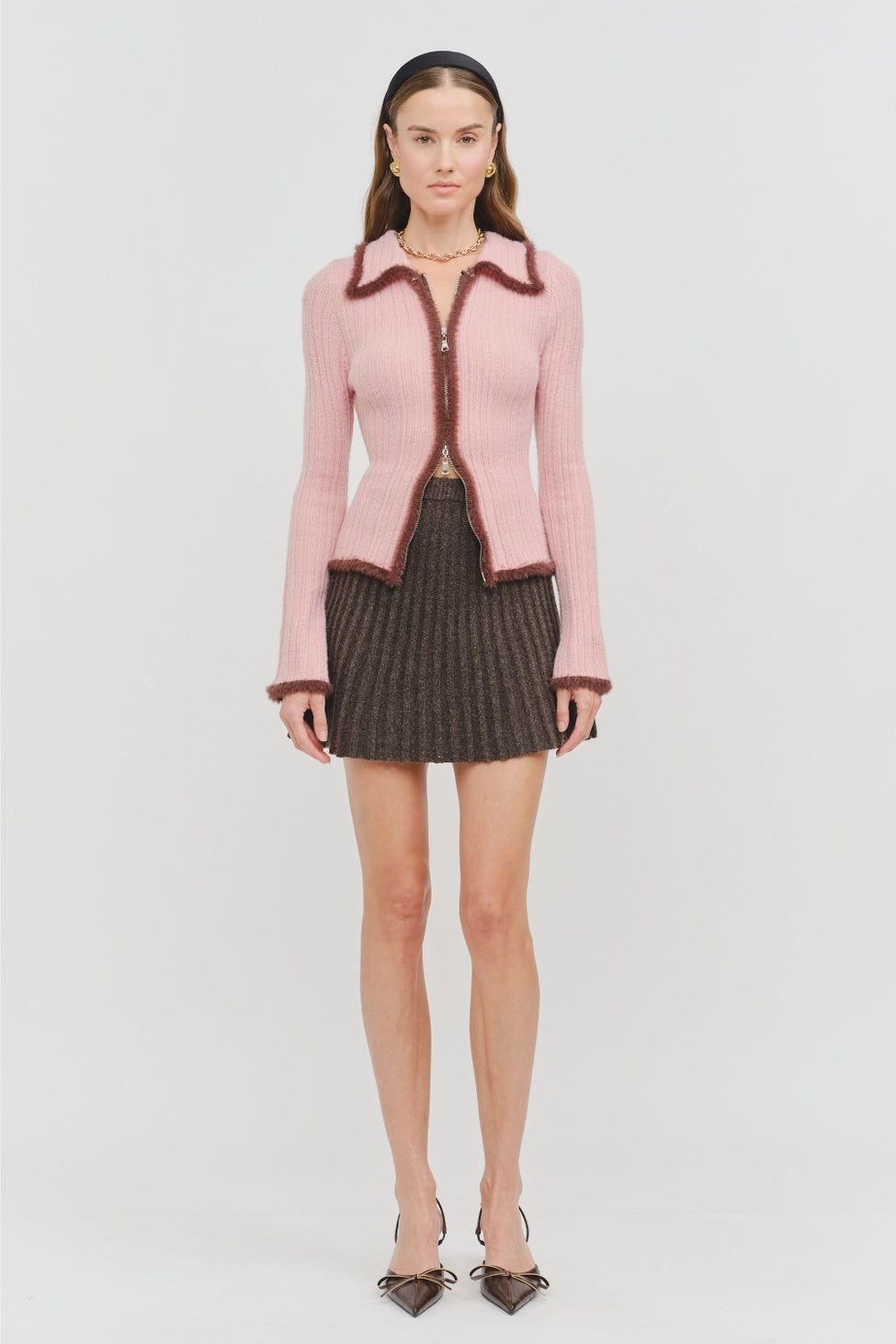 Model wearing the Jacquie Knit Top in light pink, featuring a fitted silhouette, long sleeves, collared neckline, contrasting burgundy fuzzy trim, and two-way front zipper closure.