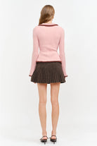 Model wearing the Jacquie Knit Top in light pink, featuring a fitted silhouette, long sleeves, collared neckline, contrasting burgundy fuzzy trim, and two-way front zipper closure.
