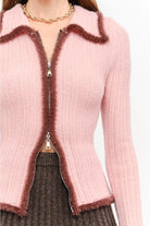 Model wearing the Jacquie Knit Top in light pink, featuring a fitted silhouette, long sleeves, collared neckline, contrasting burgundy fuzzy trim, and two-way front zipper closure.
