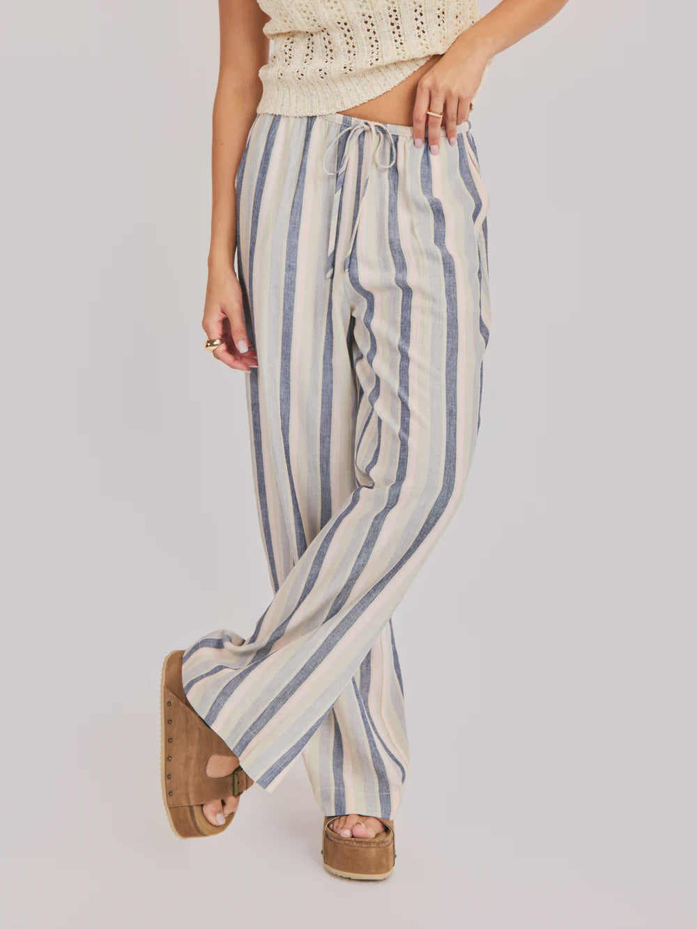 Woman wearing striped blue multi pants on a plain background