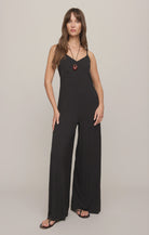 Model wearing the Z Supply Leyla Jumpsuit in black. The sleeveless jumpsuit features thin adjustable spaghetti straps, a V-neckline, a relaxed bodice with subtle seam detailing, and wide-leg pants that drape to the floor. 