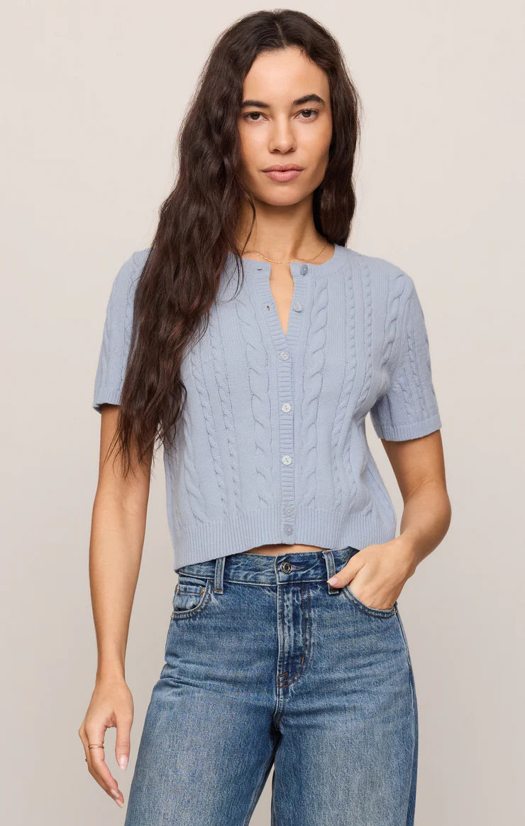 Model wearing a regular-fit cable knit cardigan with a crew neckline, short sleeves, and a button-front closure. 