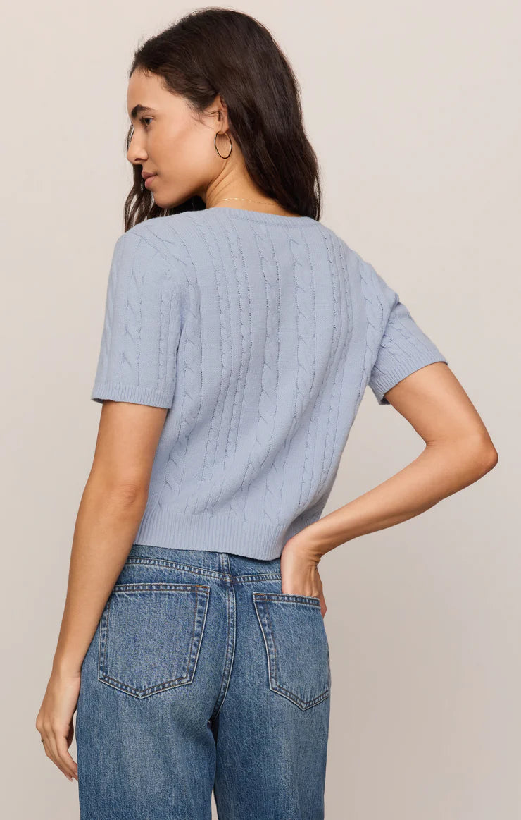 Model wearing a regular-fit cable knit cardigan with a crew neckline, short sleeves, and a button-front closure. 