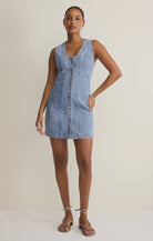 Woman wearing a denim button down mini dress against a plain background