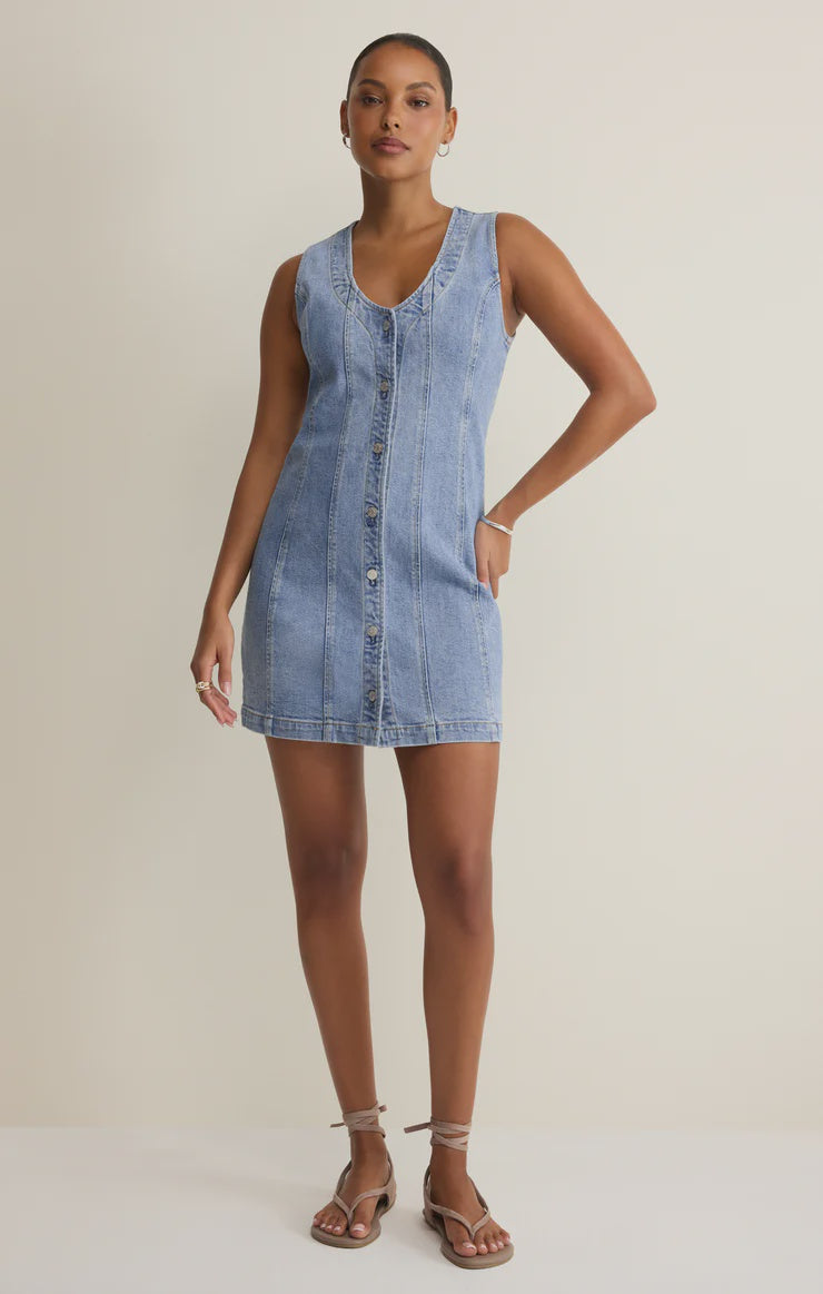 Woman wearing a denim button down mini dress against a plain background