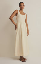 Woman wearing an off white sleeveless poplin dress against a plain background