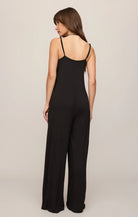Model wearing the Z Supply Leyla Jumpsuit in black. The sleeveless jumpsuit features thin adjustable spaghetti straps, a V-neckline, a relaxed bodice with subtle seam detailing, and wide-leg pants that drape to the floor. 