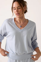 Model wearing a sky-blue V-neck sweatshirt with long sleeves, ribbed cuffs and hem, and a relaxed fit.