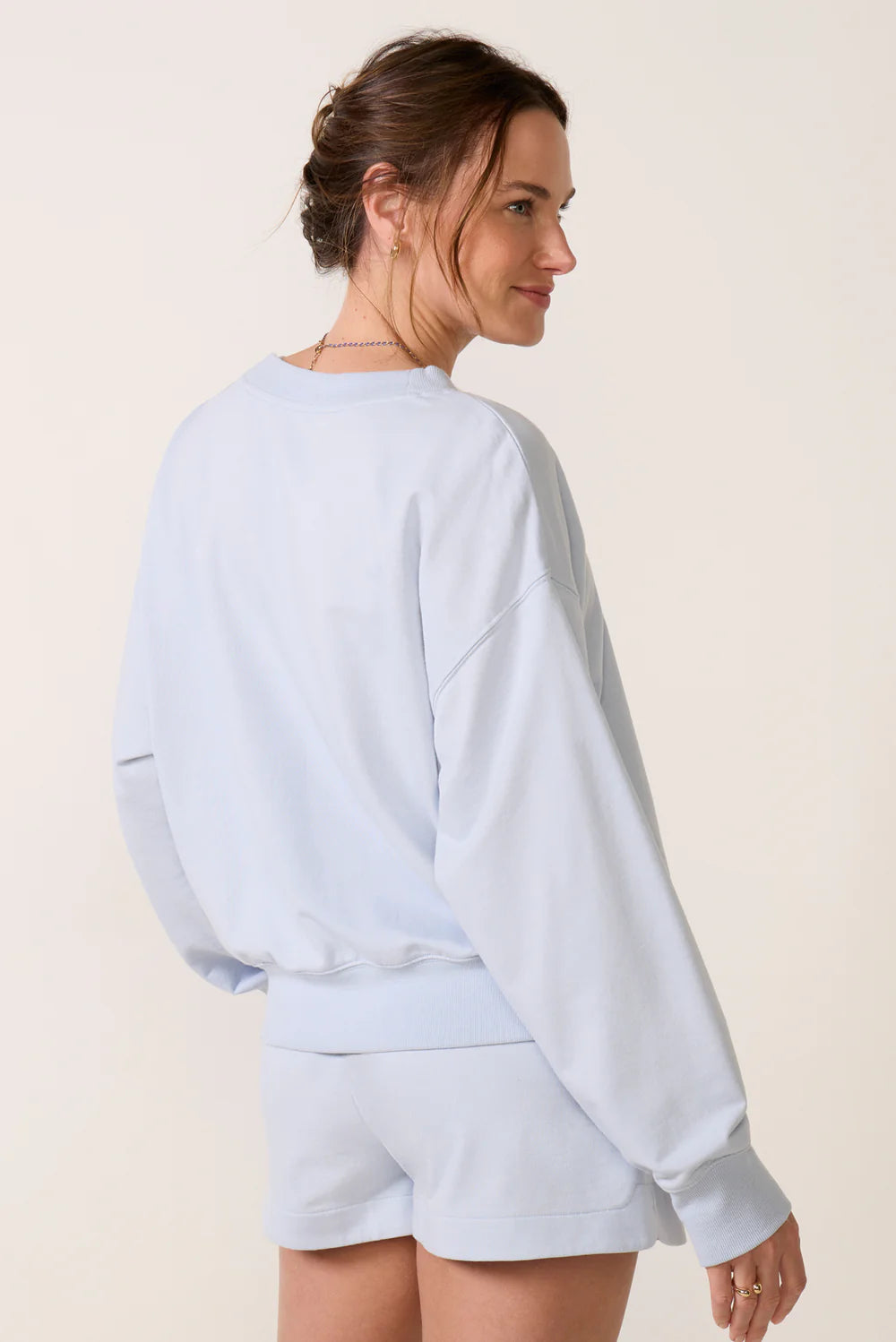 Model wearing a sky-blue V-neck sweatshirt with long sleeves, ribbed cuffs and hem, and a relaxed fit.