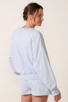 Model wearing a sky-blue V-neck sweatshirt with long sleeves, ribbed cuffs and hem, and a relaxed fit.