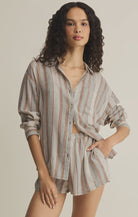 Woman wearing a striped shirt and shorts set on a beige background
