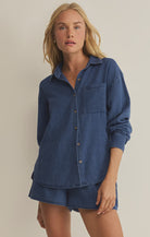 Woman wearing a blue denim shirt and shorts on a beige background